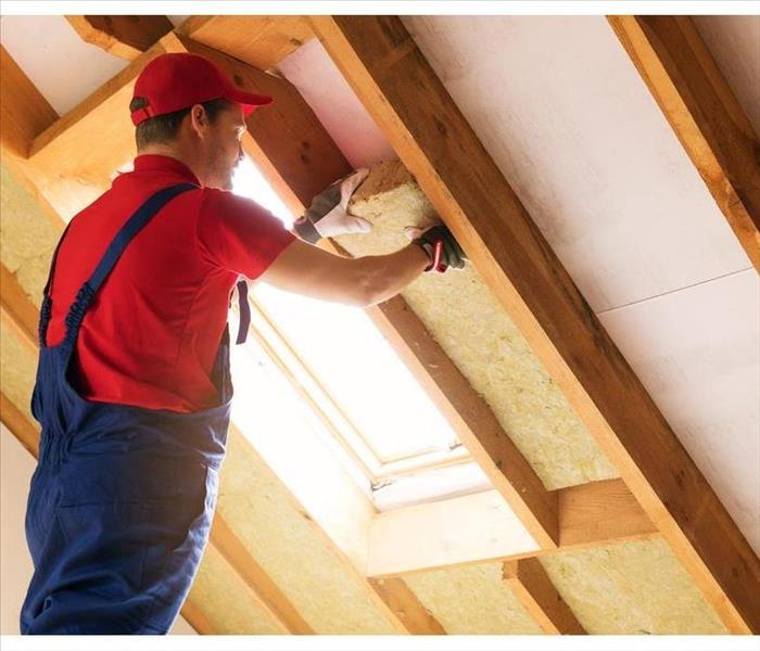 Man installing insulation in an attic.