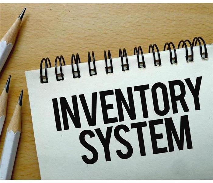 Note pad with words written " Inventory System" with three pencils.